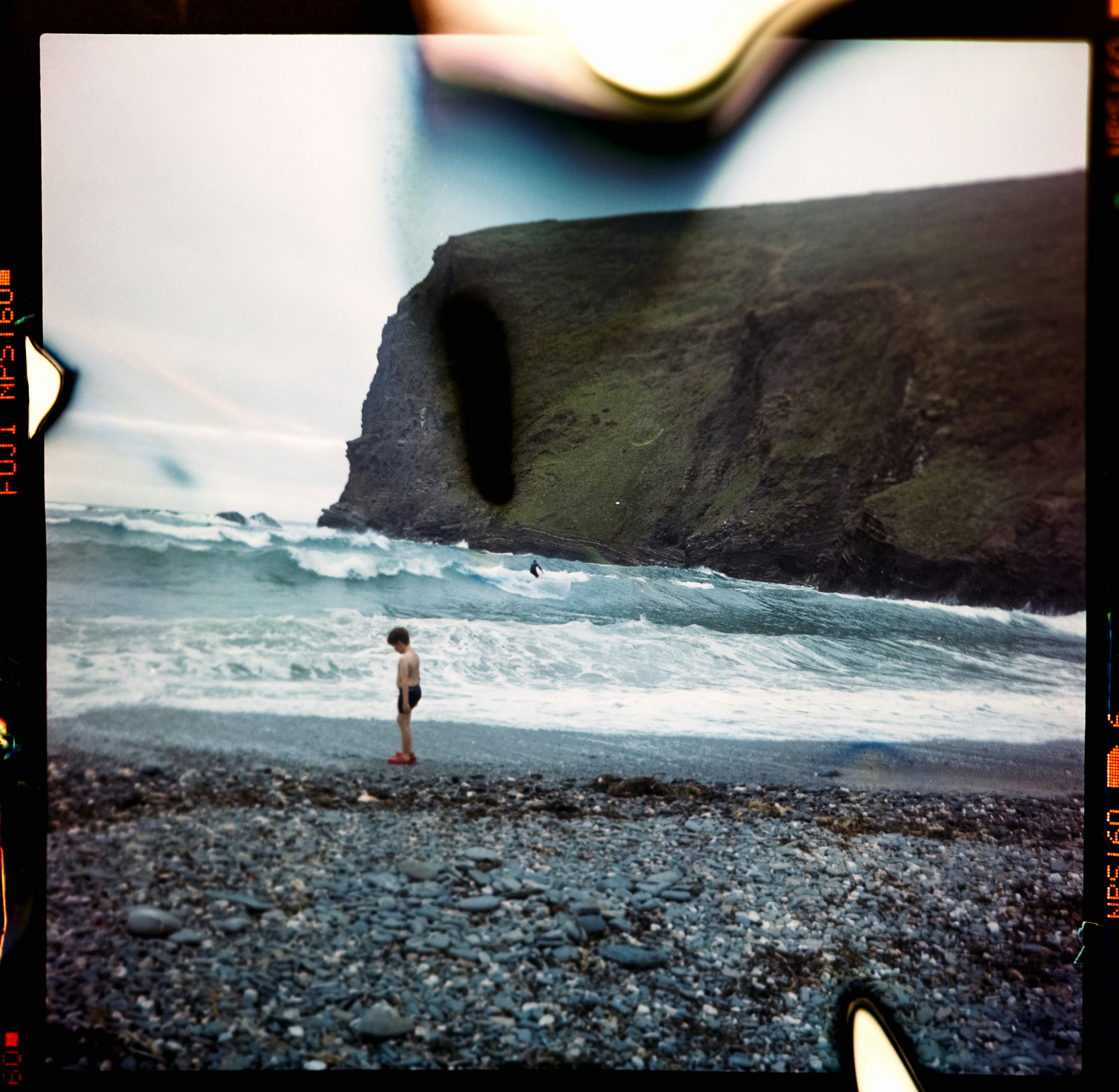 person in black pants standing on gray rocky shore during daytime